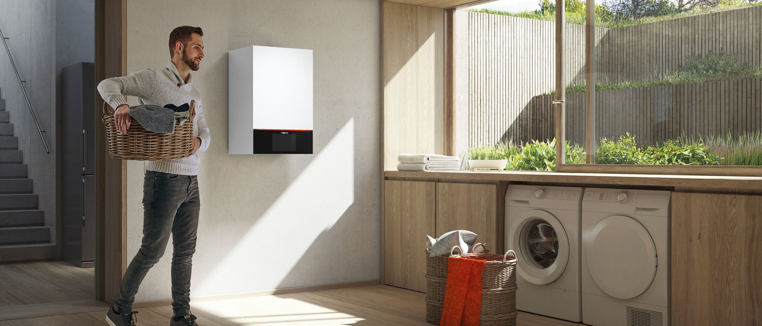 White and black wall-mounted hydronic boiler installed in a laundry room above wooden cabinetry.