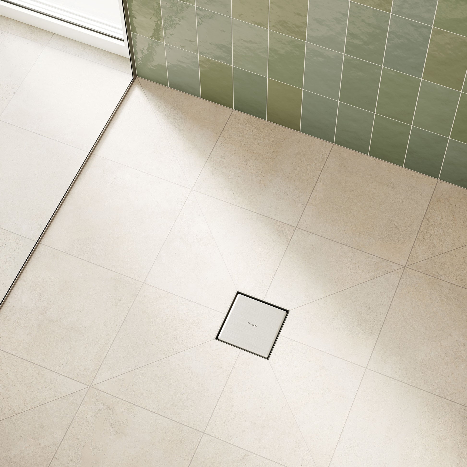 Square brushed stainless steel floor drain with black trim installed in beige tile shower floor.