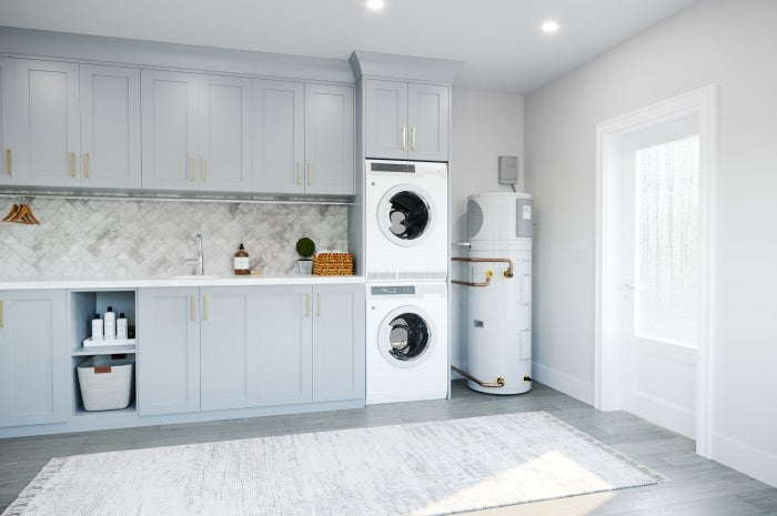 White cylindrical electric heat pump water heater standing upright in laundry room next to stacked washers and dryers.