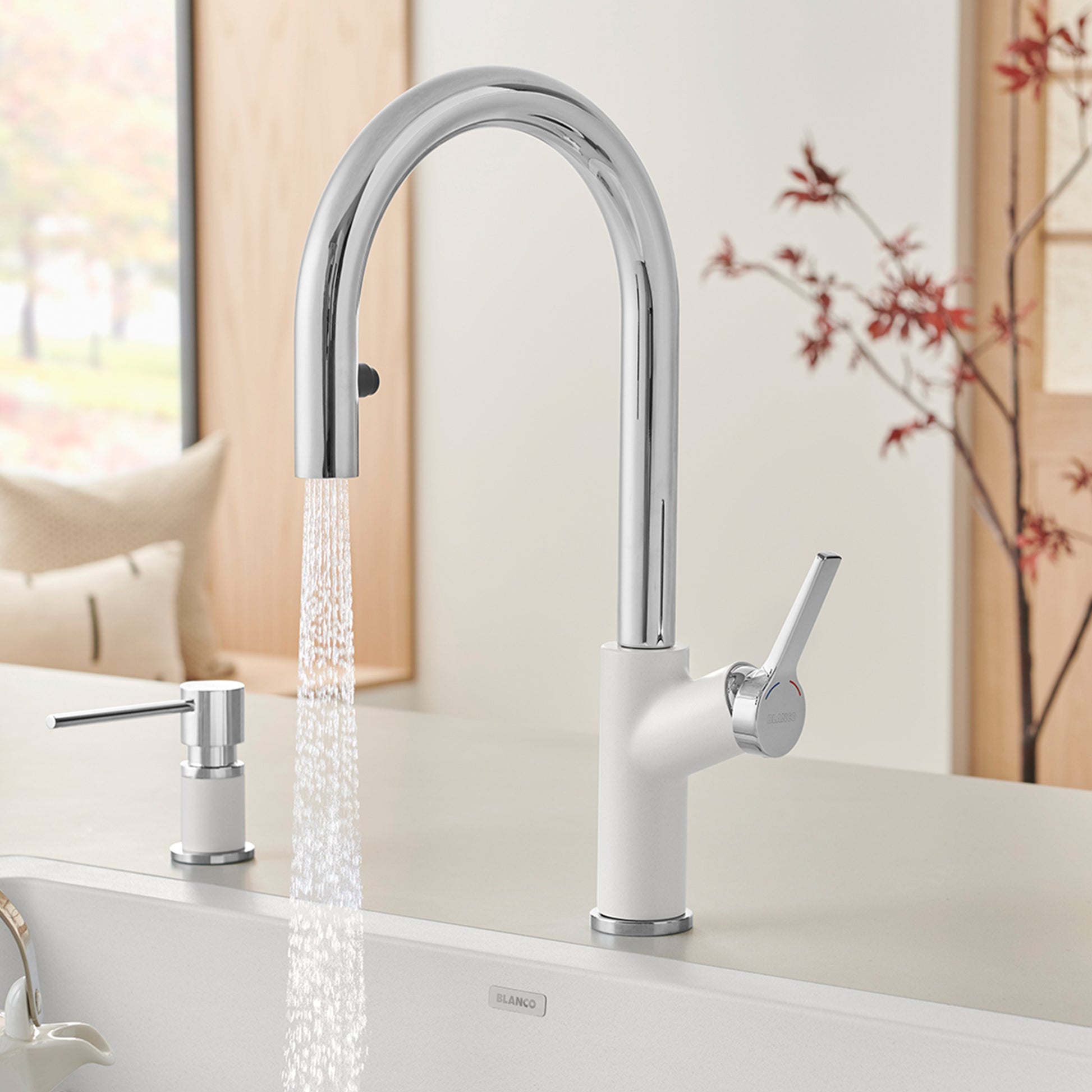 Chrome and white pull-down kitchen faucet with arched spout and single lever handle, shown installed with water running.