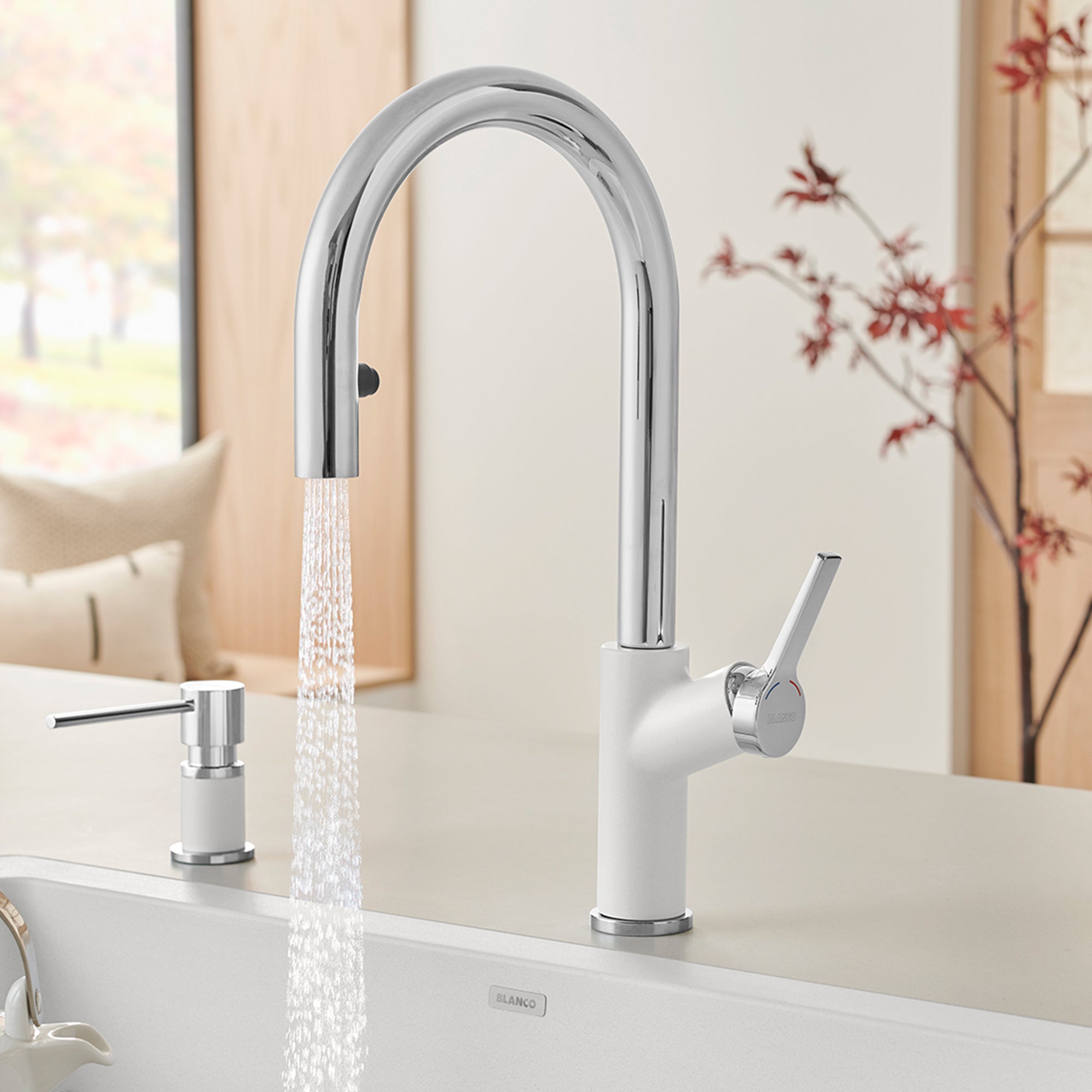 Chrome and white pull-down kitchen faucet with arched spout and single lever handle, shown installed with water running.