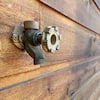 Freezeless wall faucet with metal handle mounted on wooden exterior wall.
