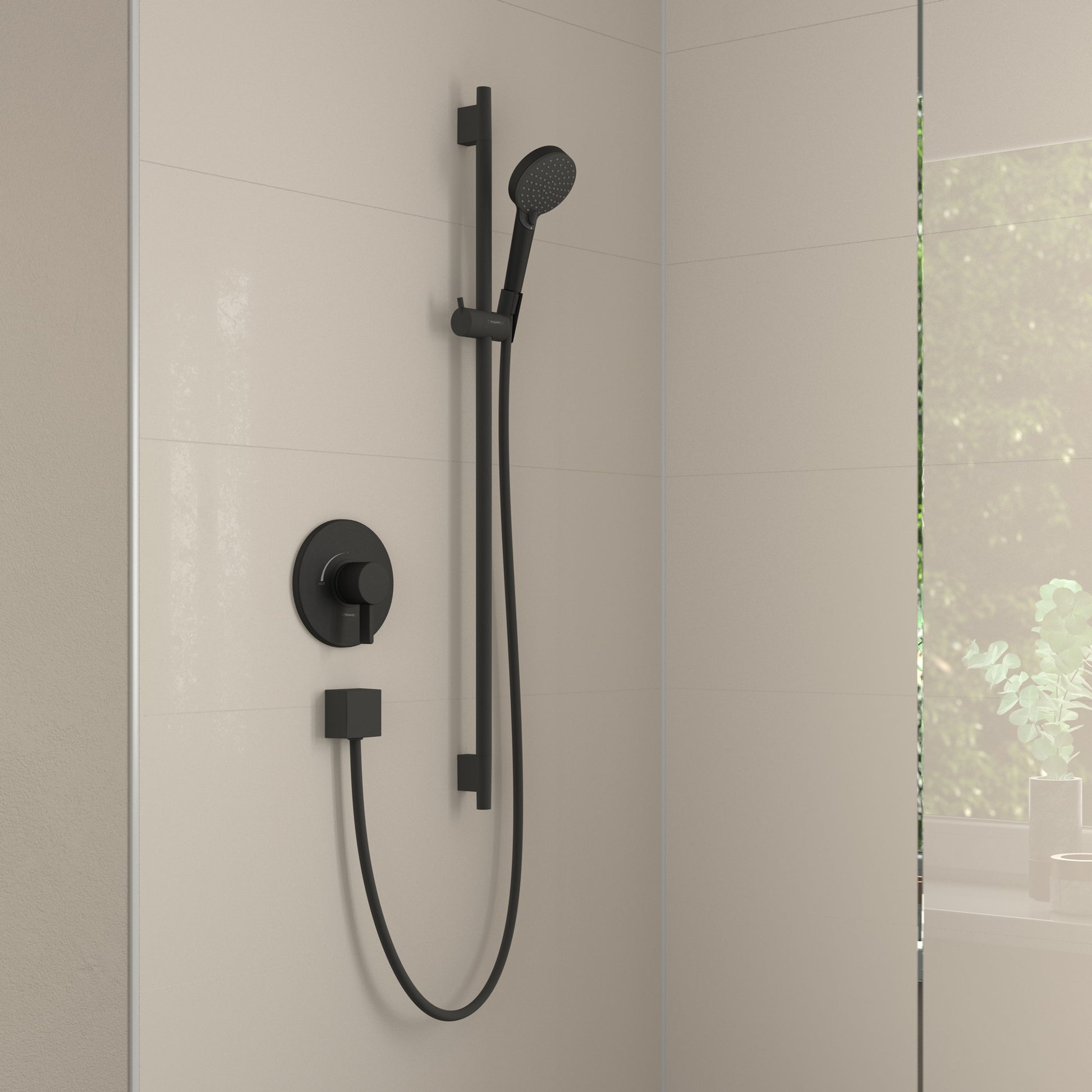 Matte black handheld shower system with round wall-mounted trim, vertical rail, and connected hose installed on tile wall.