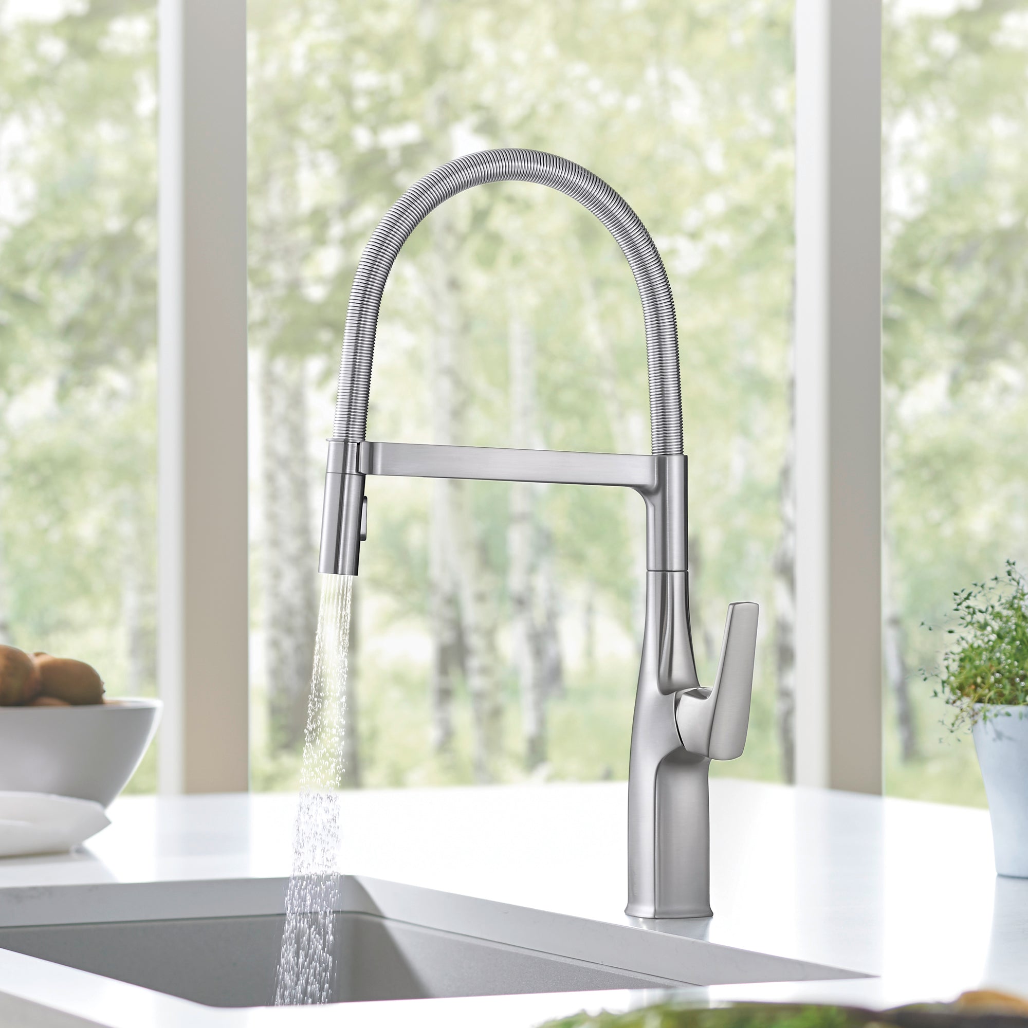 Stainless steel kitchen faucet with high arched spout, flexible hose, and single lever handle dispensing water into sink.