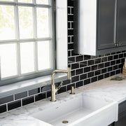 Polished nickel soap dispenser pump mounted on white marble countertop next to kitchen sink.