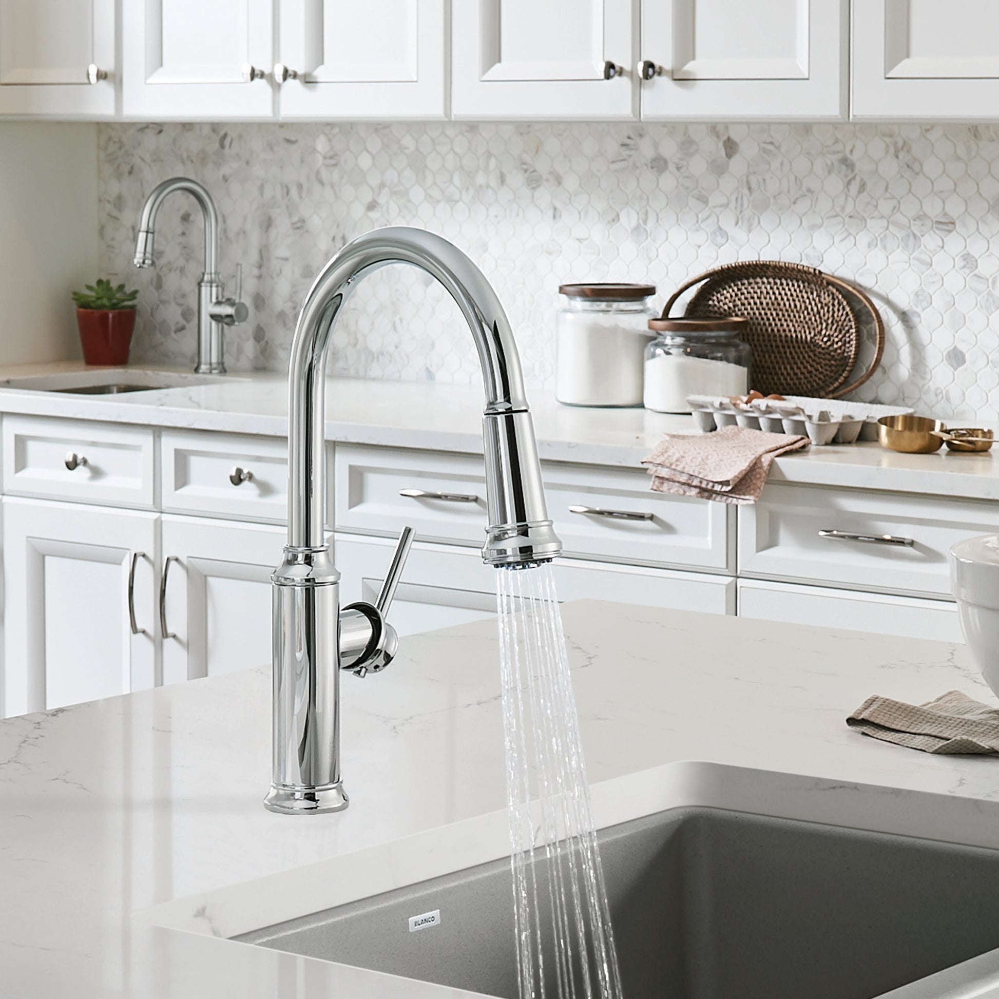 Chrome pull-down kitchen faucet with curved spout and single lever handle installed over undermount sink in white cabinet.