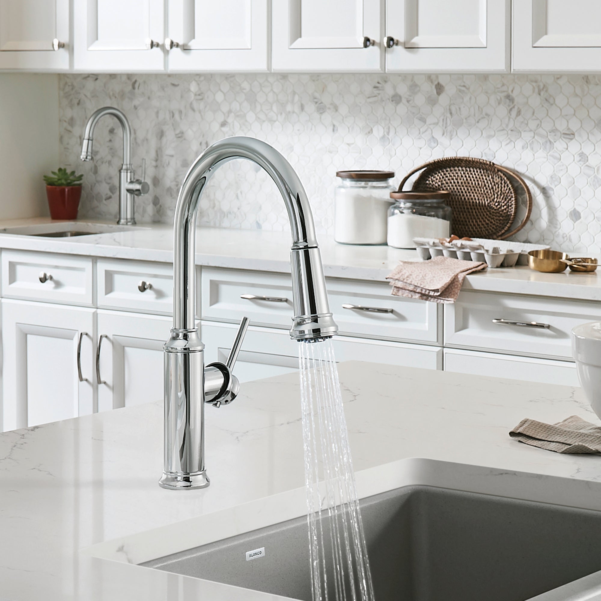 Chrome pull-down kitchen faucet with curved spout and single lever handle installed over undermount sink in white cabinet.