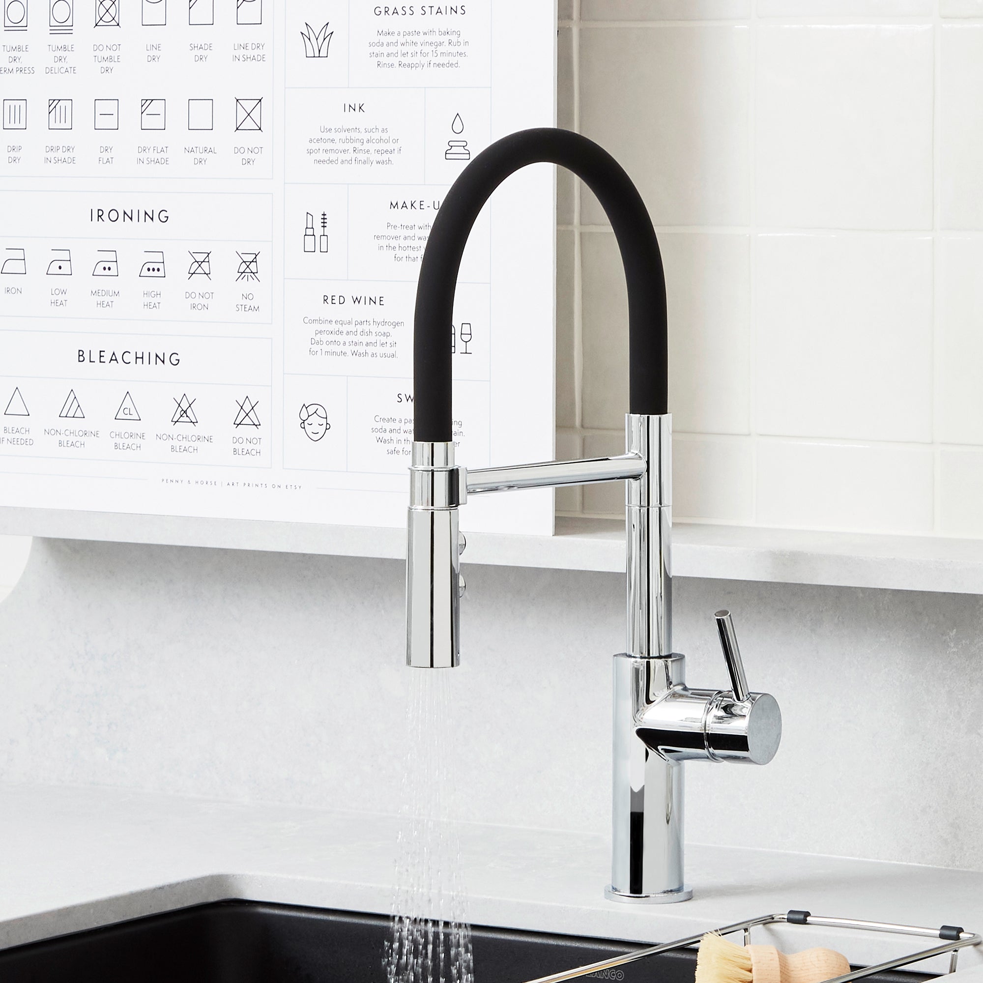 Chrome kitchen faucet with black flexible hose and single lever handle installed above sink.