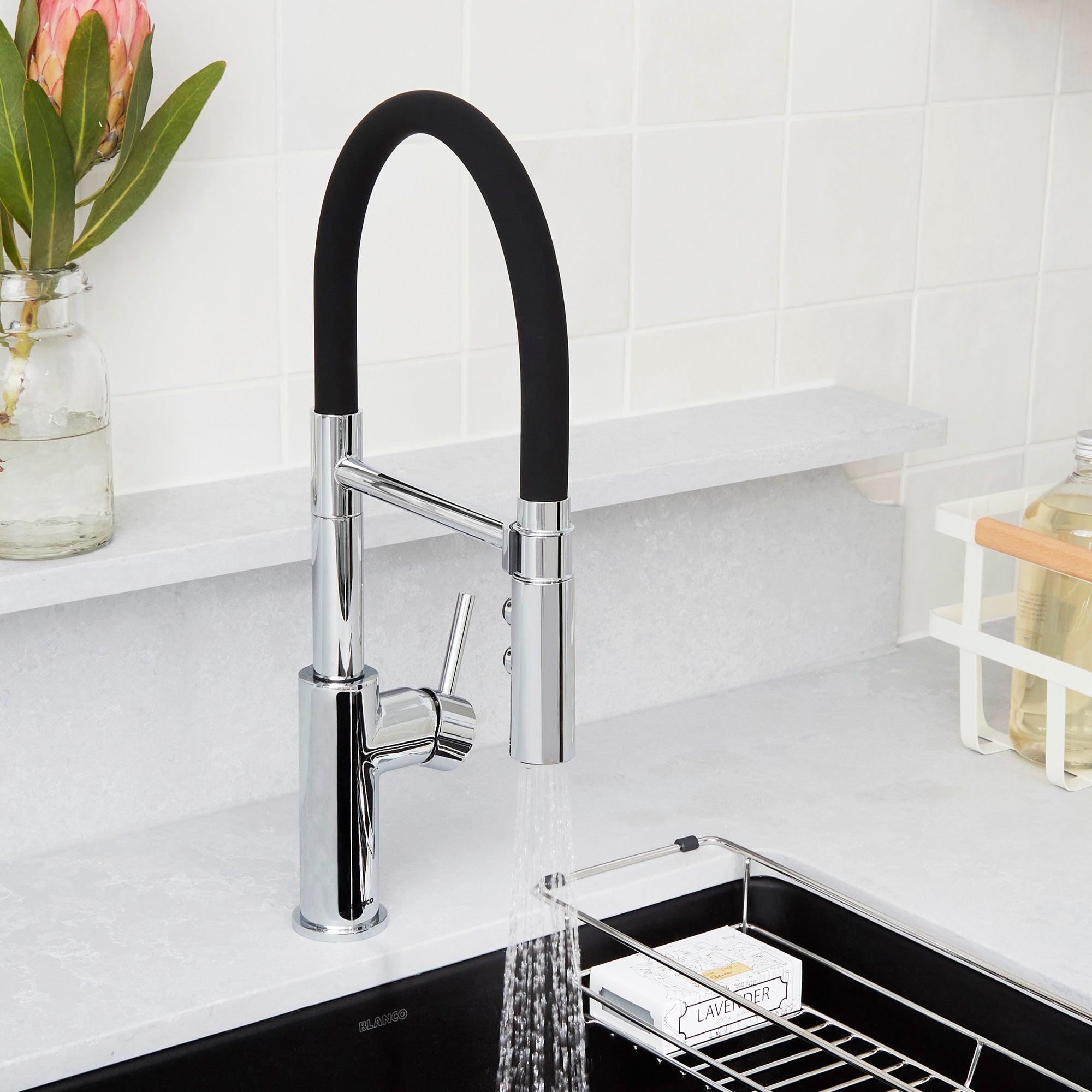 Chrome kitchen faucet with black flexible hose and single lever handle above black sink basin.