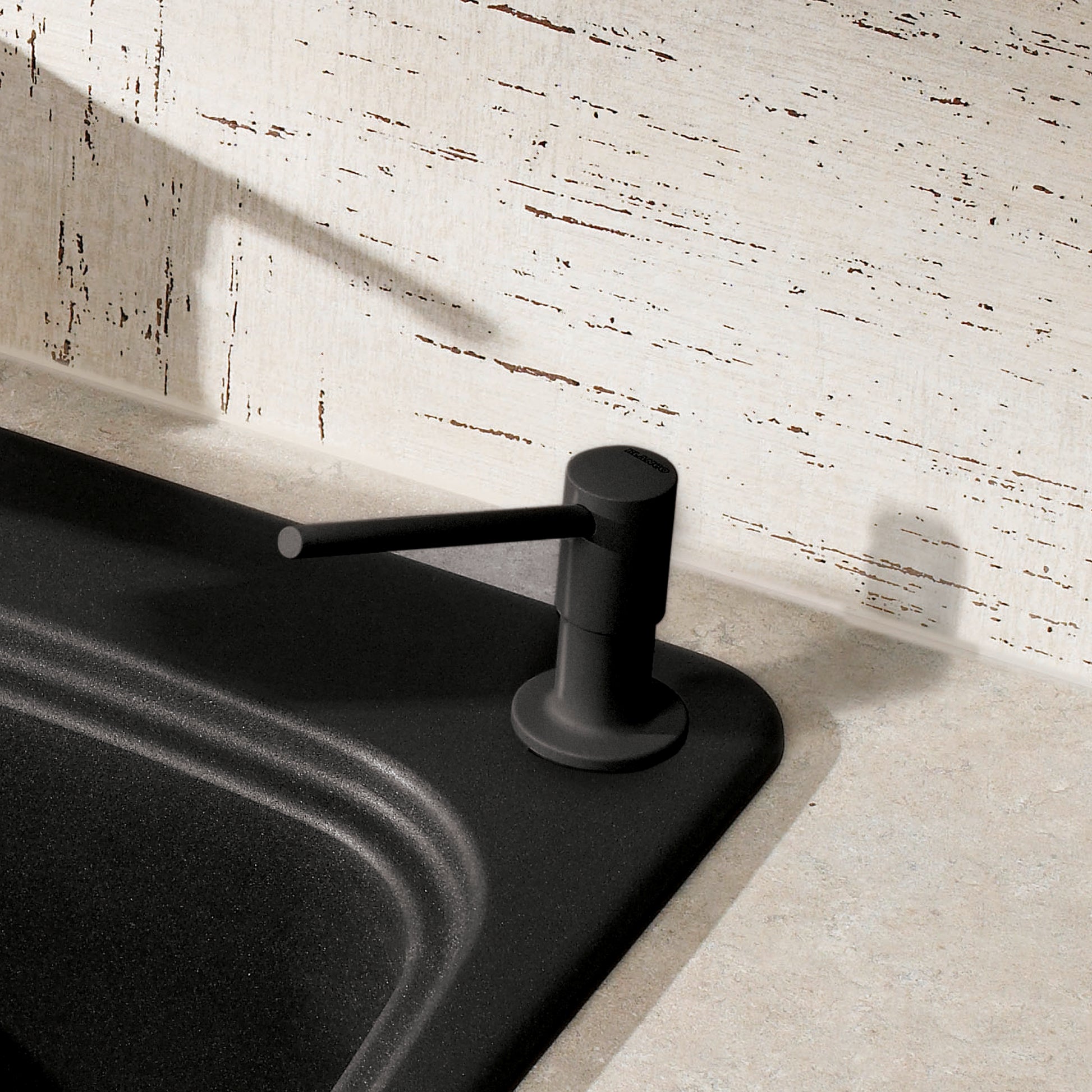 Anthracite soap dispenser with cylindrical pump mounted on black sink counter next to whitewashed wooden wall.
