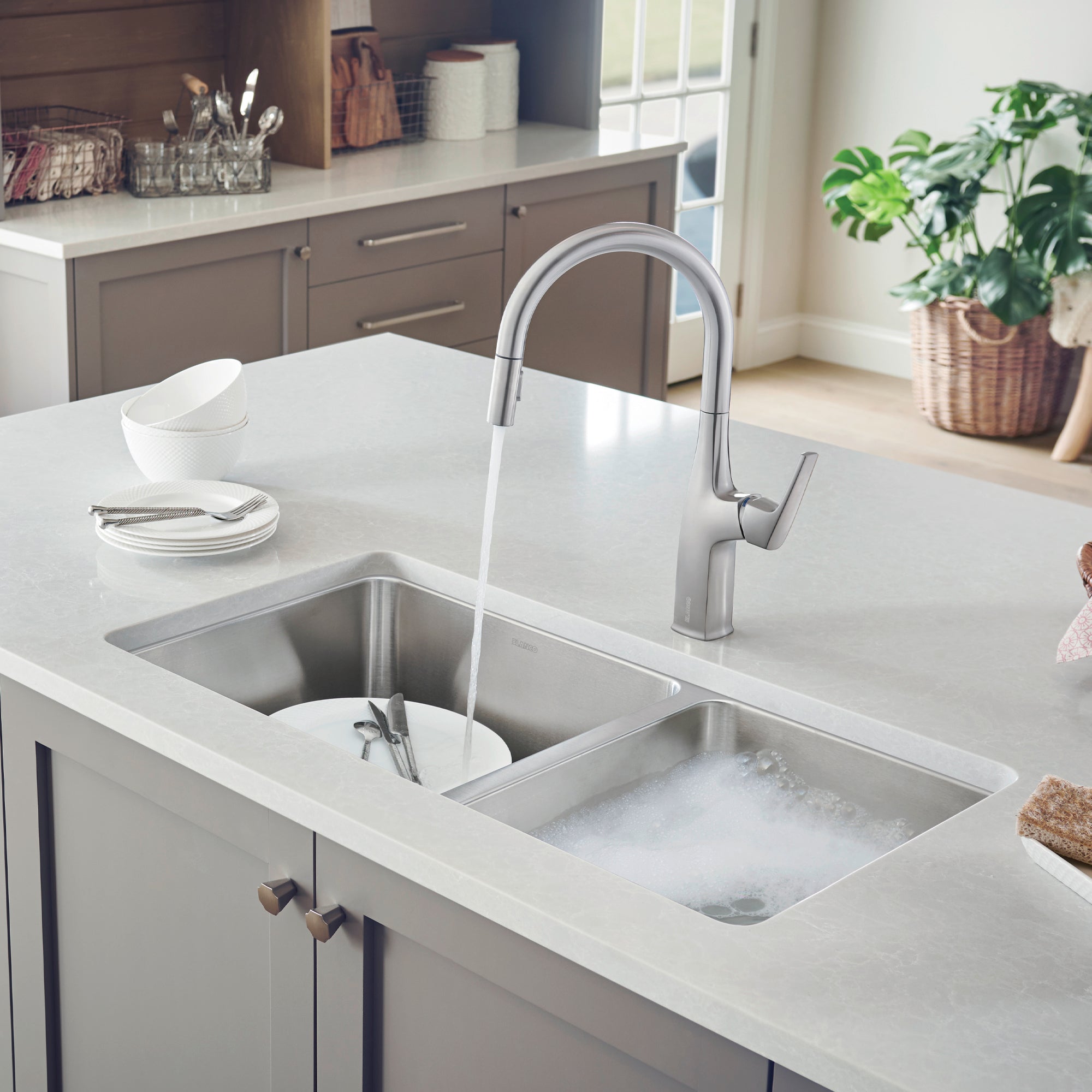 Stainless steel undermount double bowl sink with left bowl filled with soapy water and right bowl empty, installed in white q