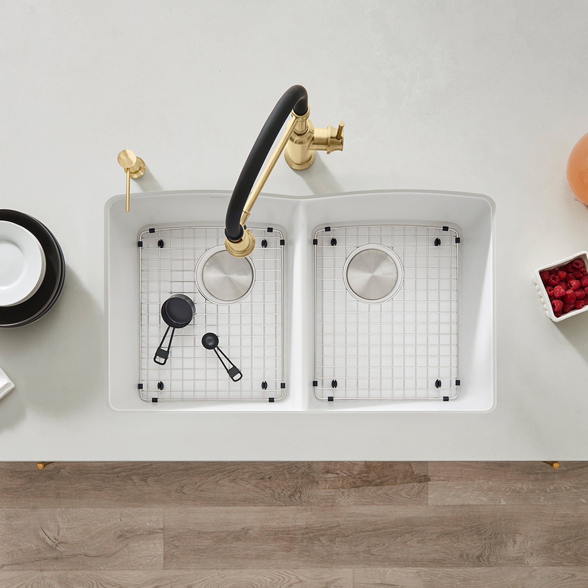 Stainless steel sink grid with square pattern fitting inside white double-basin sink basin.