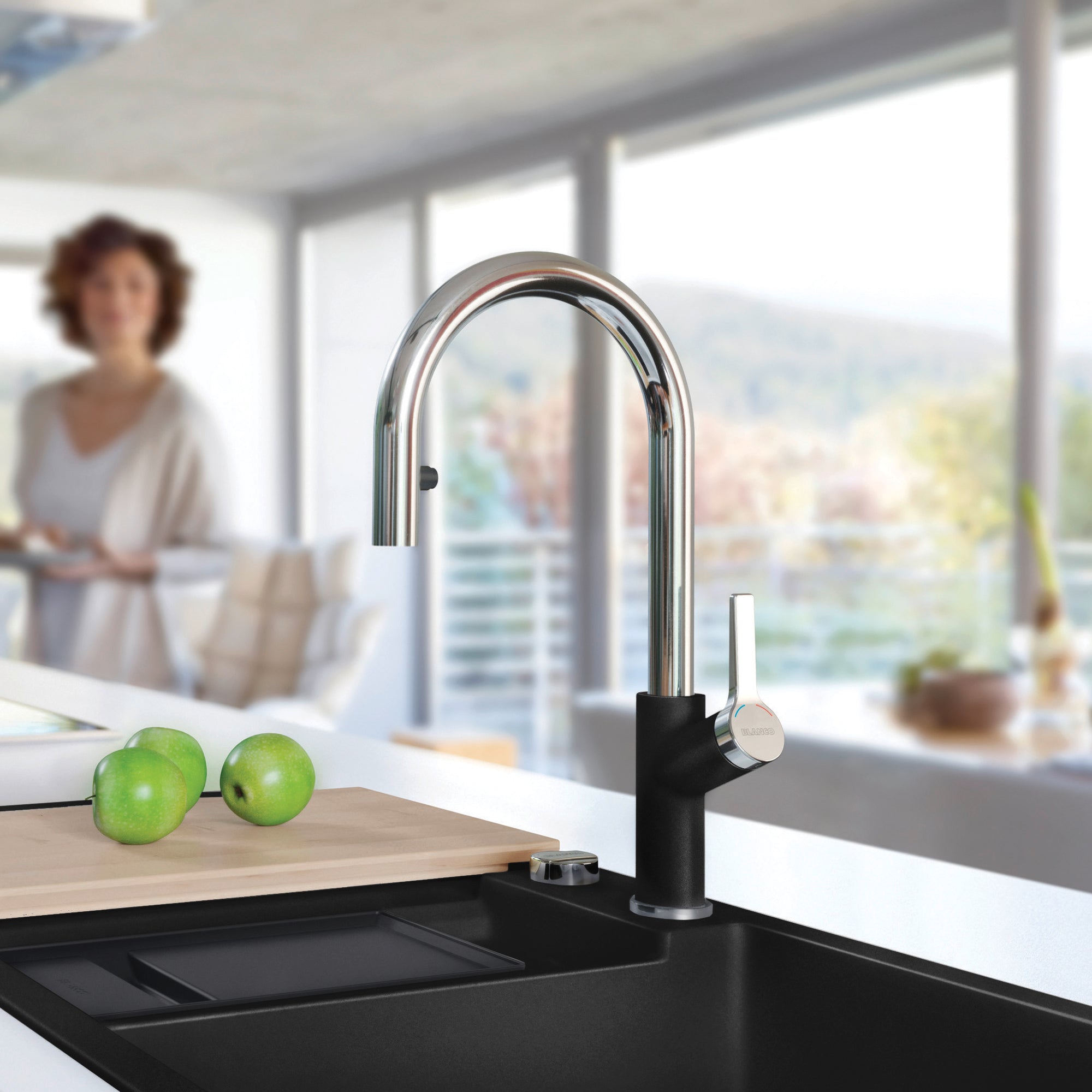 Chrome and black pull-down kitchen faucet with curved spout mounted on black sink in modern kitchen.
