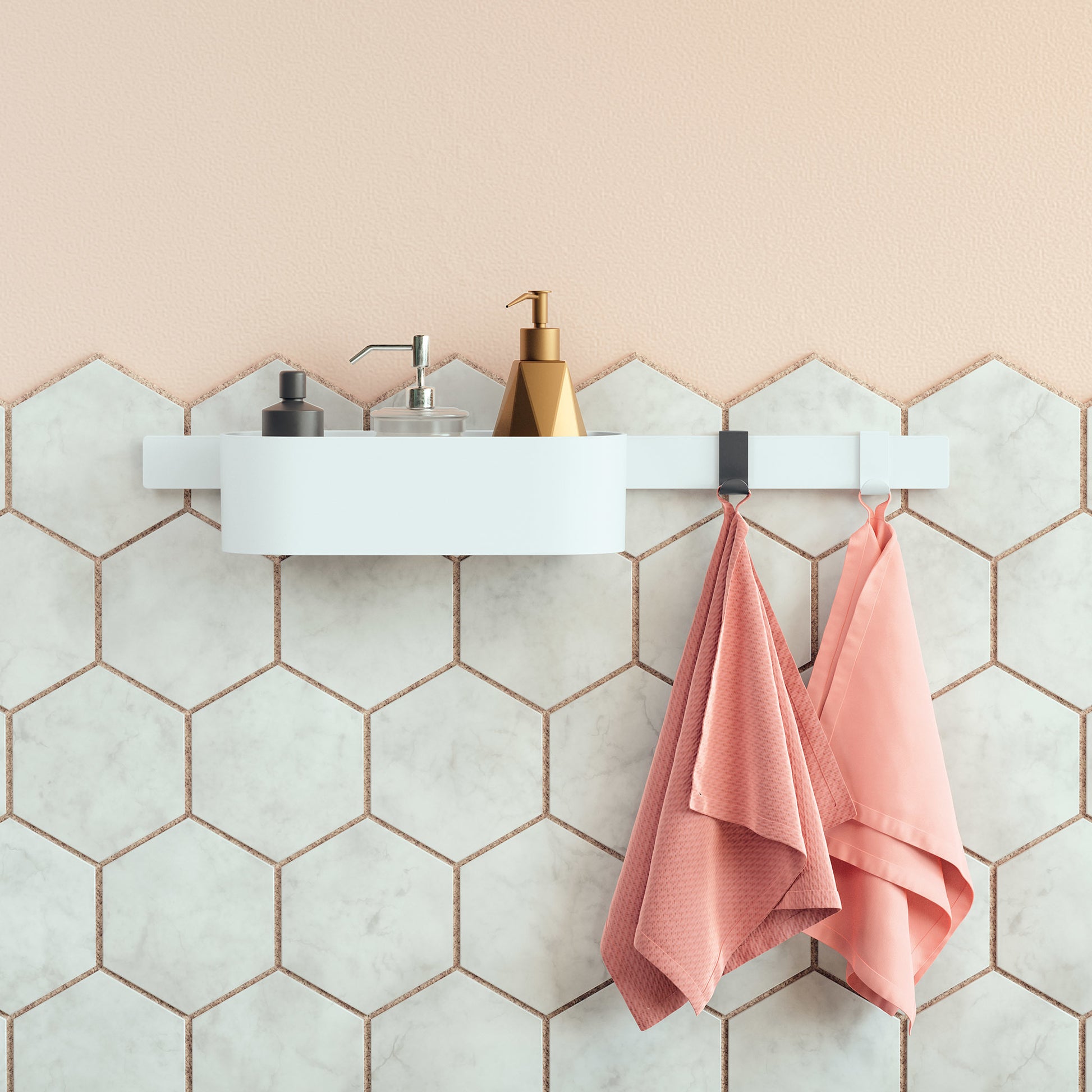 Matte white rectangular wall-mounted storage basket holding bathroom items above hexagonal tile wall with hanging towels.