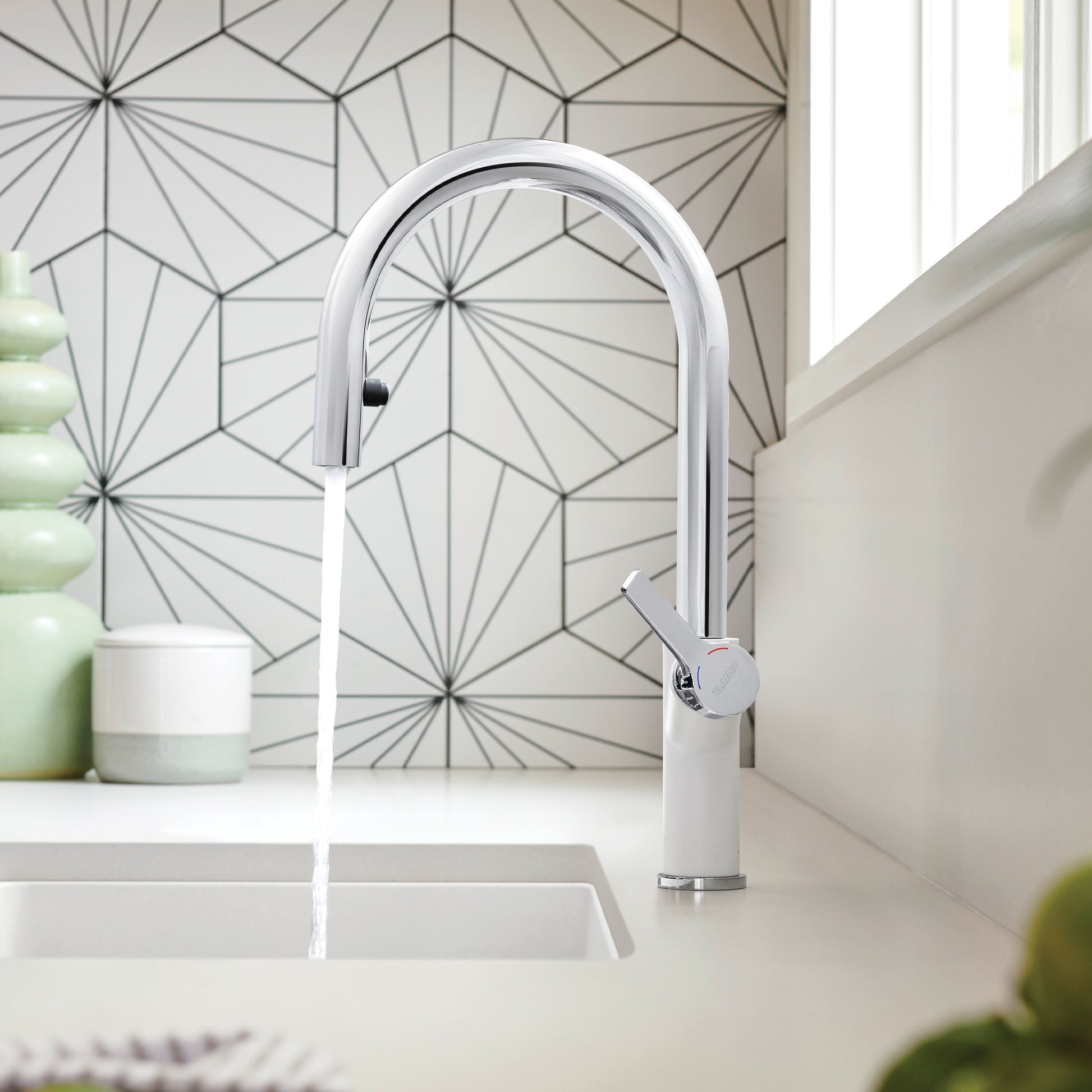 Chrome and white pull-down kitchen faucet with curved spout over sink in modern kitchen.