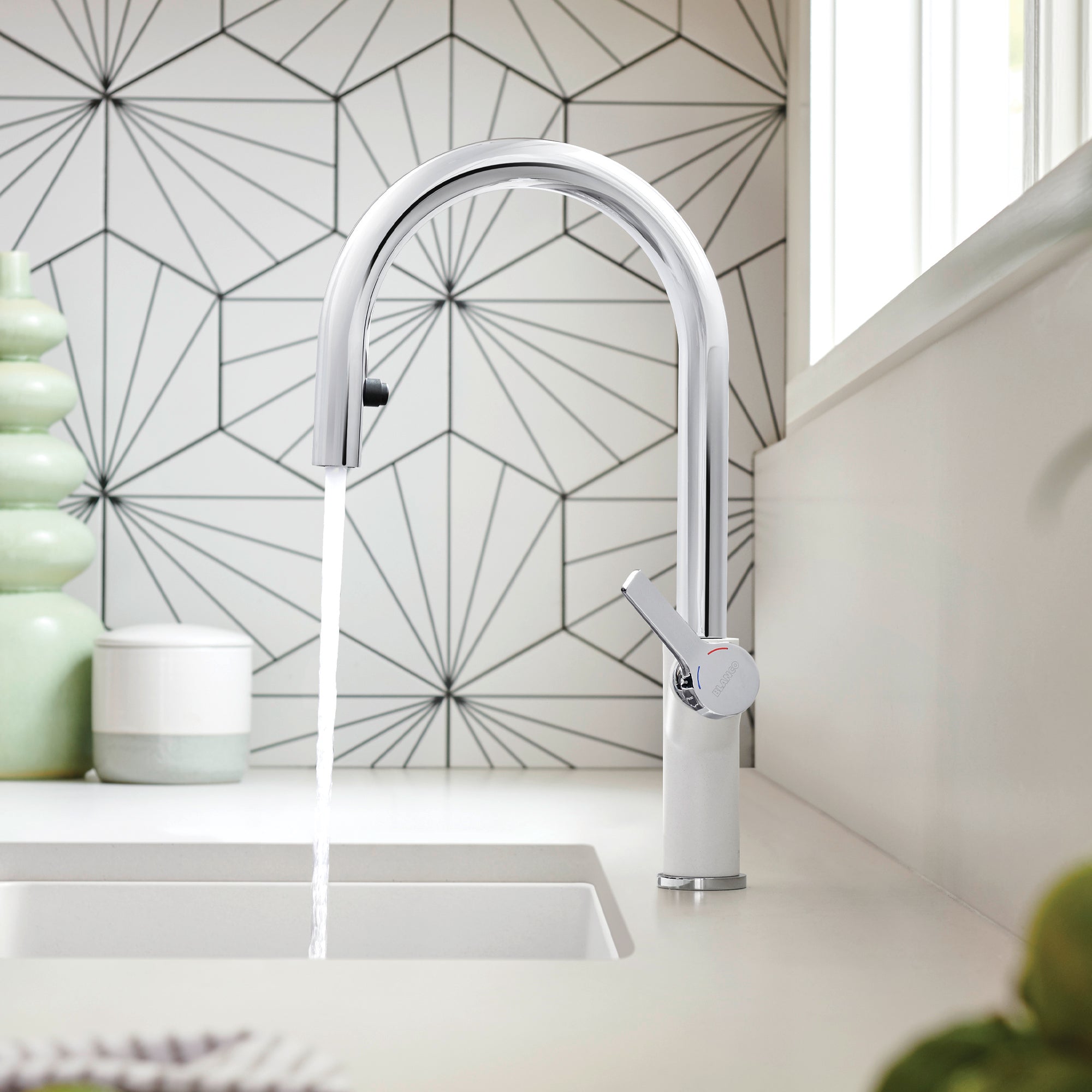 Chrome and white pull-down kitchen faucet with curved spout over sink in modern kitchen.