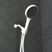 Matte white handheld showerhead with black perforated face mounted on vertical rail against herringbone tile wall.