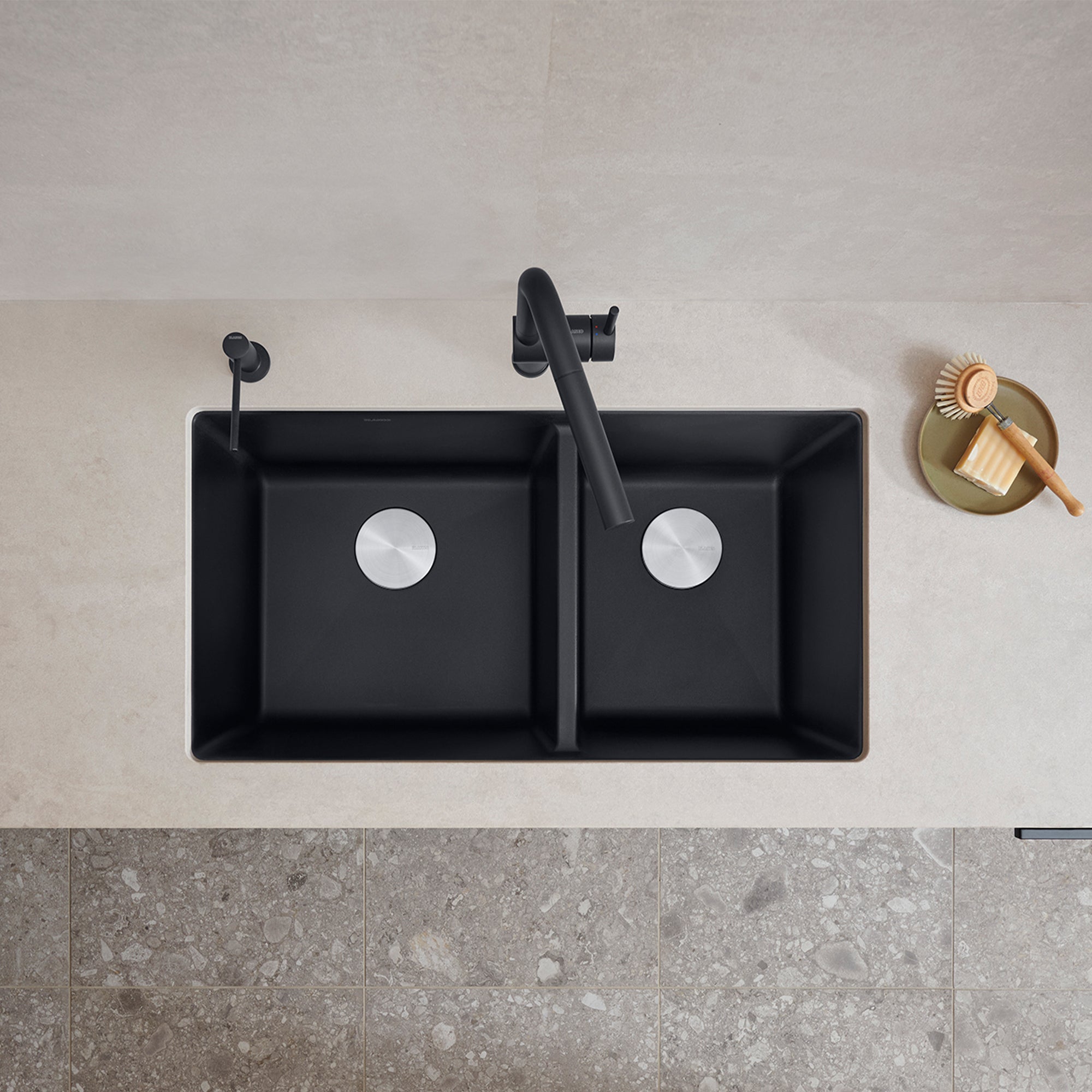 Coal black double bowl undermount kitchen sink with unequal 60/40 basins, chrome drain strainers, and black faucet.