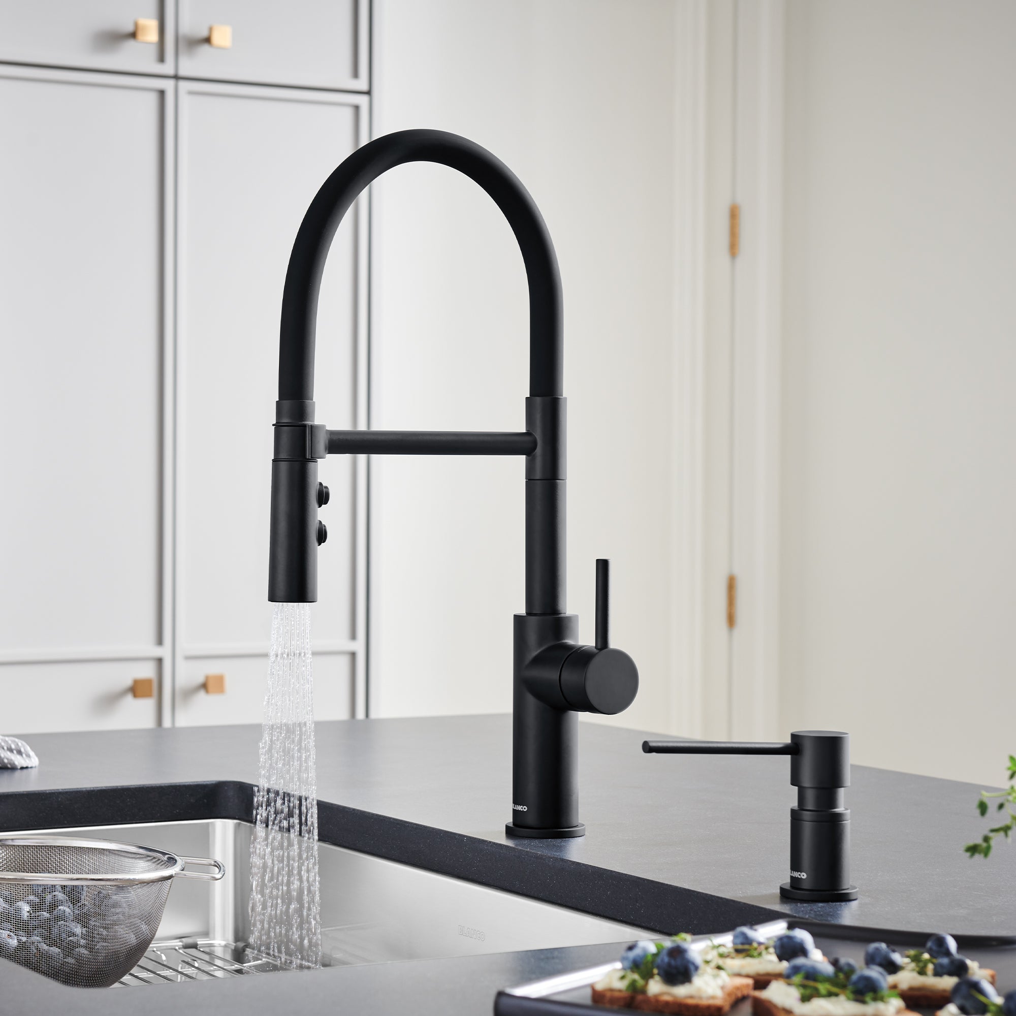 Matte black pull-down kitchen faucet with flexible hose, control buttons, and matching soap dispenser on countertop.