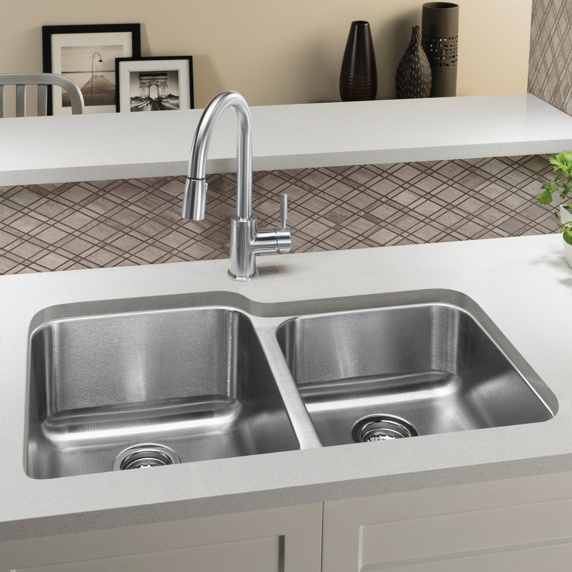 Stainless steel double bowl undermount sink with chrome pull-down faucet installed in white countertop.