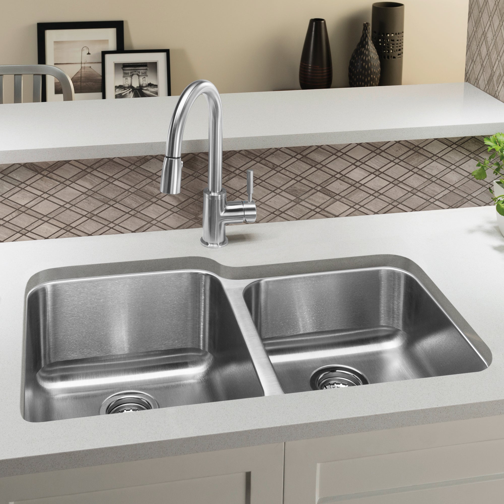 Stainless steel double bowl undermount sink with chrome pull-down faucet installed in white countertop.