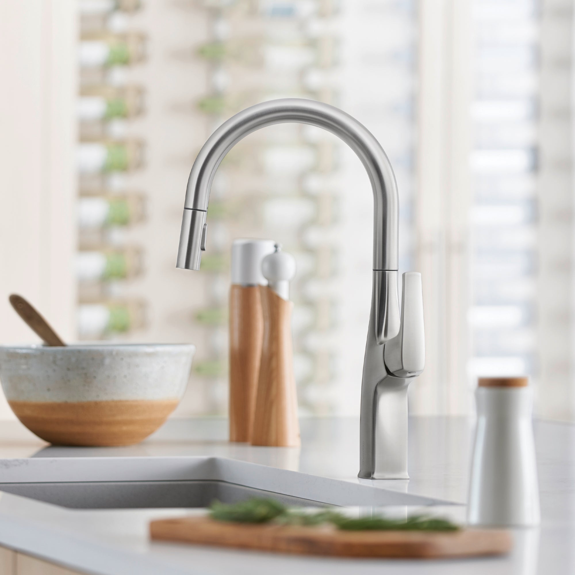 Stainless steel pull-down kitchen faucet with high arched spout and single lever handle mounted above sink.