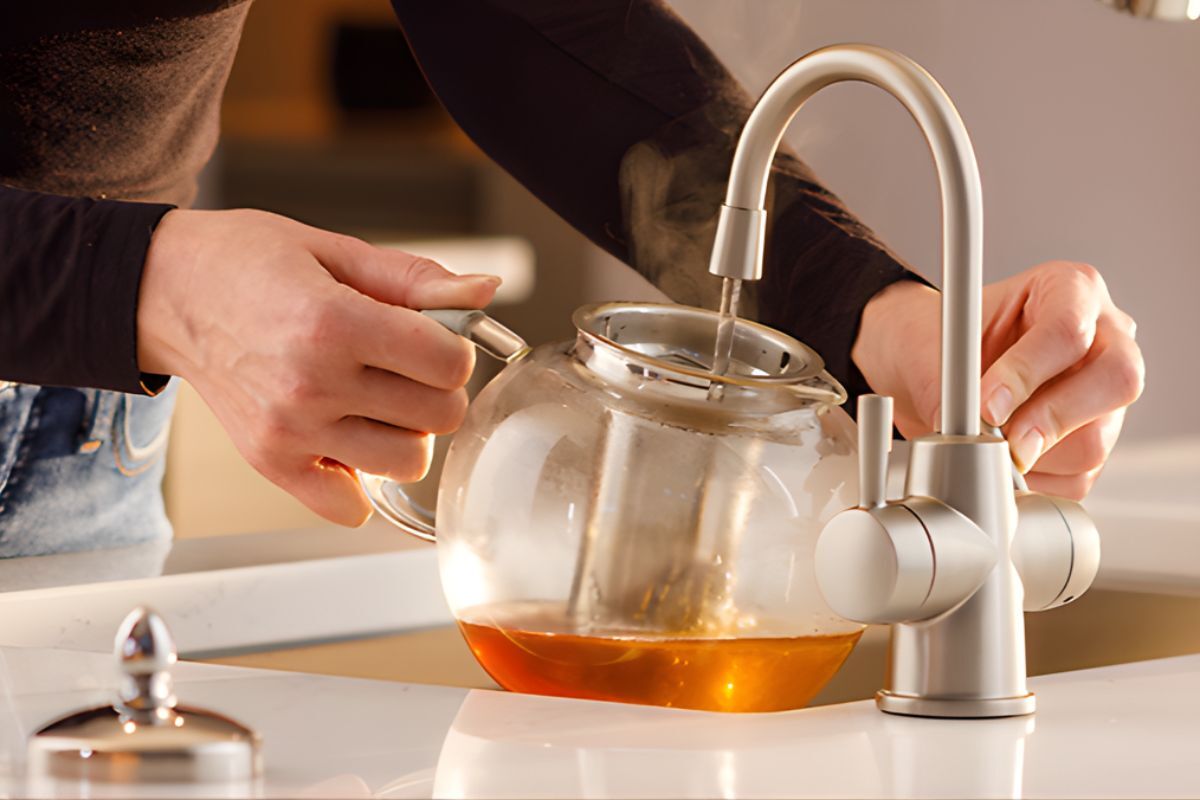 A woman in the kitchen filling up a kettle with boiling water from her instant hot water dispenser from Insinkerator