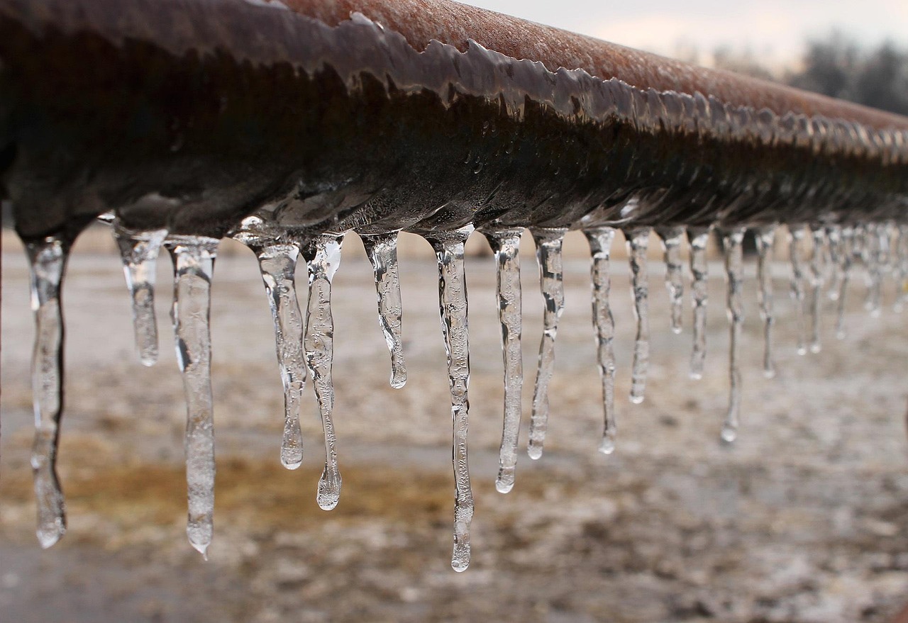 A frozen pipe covered in small icicles from being outside.
