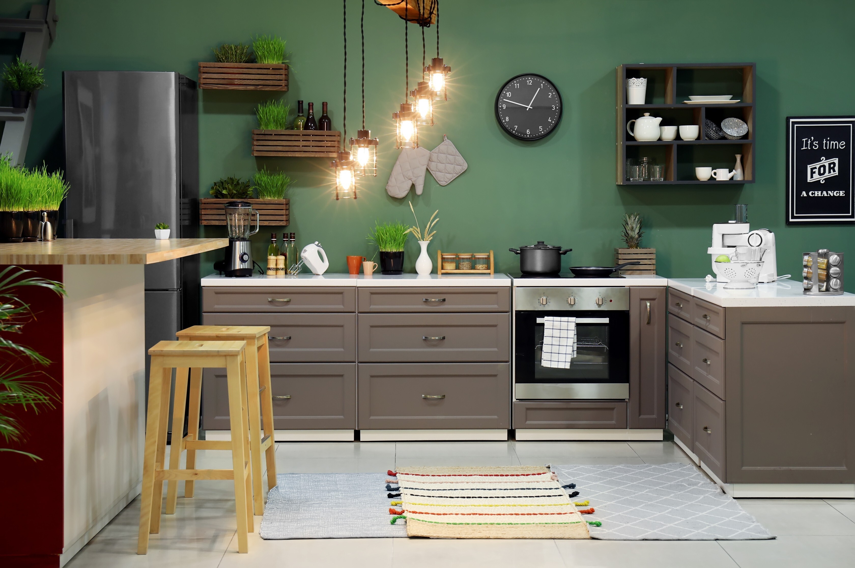 A dark green, earth tone colored kitchen with dark wood cabinets and drawers