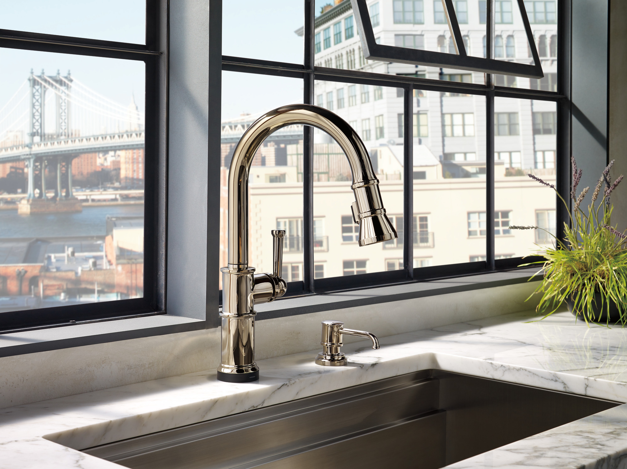 A kitchen in the city with a gold sink and matching Brizo Artesso Soap Lotion Dispenser