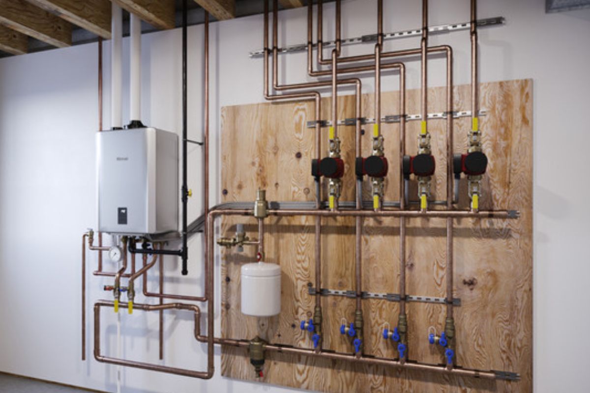 A residential wall in a boiler room with a Rinnai tankless water heater connected to the wall.