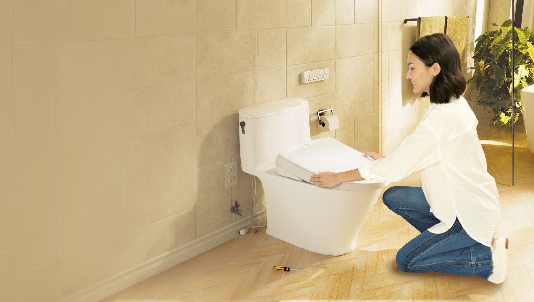 A woman kneeling over her toilet to install a TOTO Washlet from the Plumbing Deals love your bum sale with up to 20% off